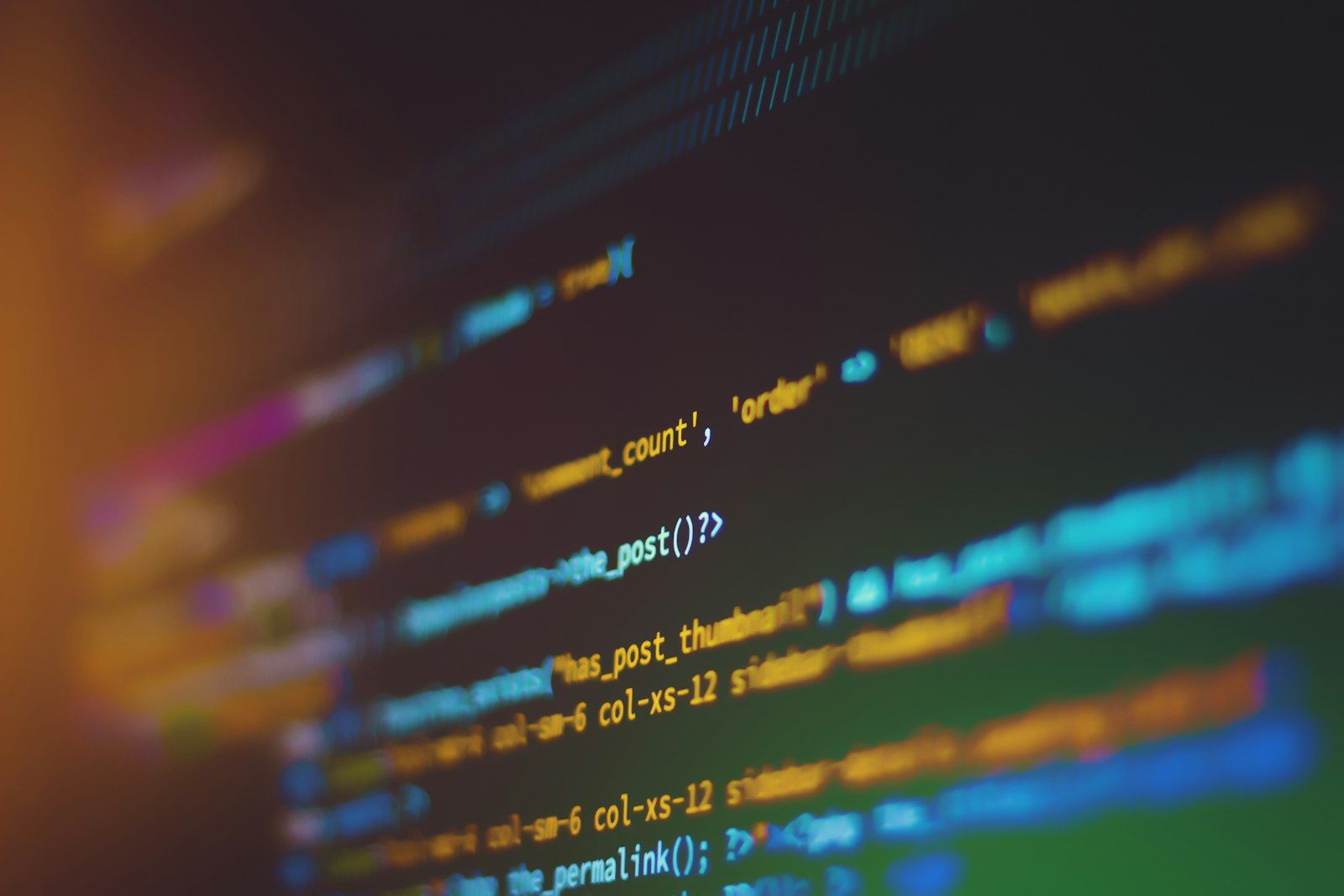 Pantalla en penumbra mostrando líneas de código desenfocadas en tonos cálidos
