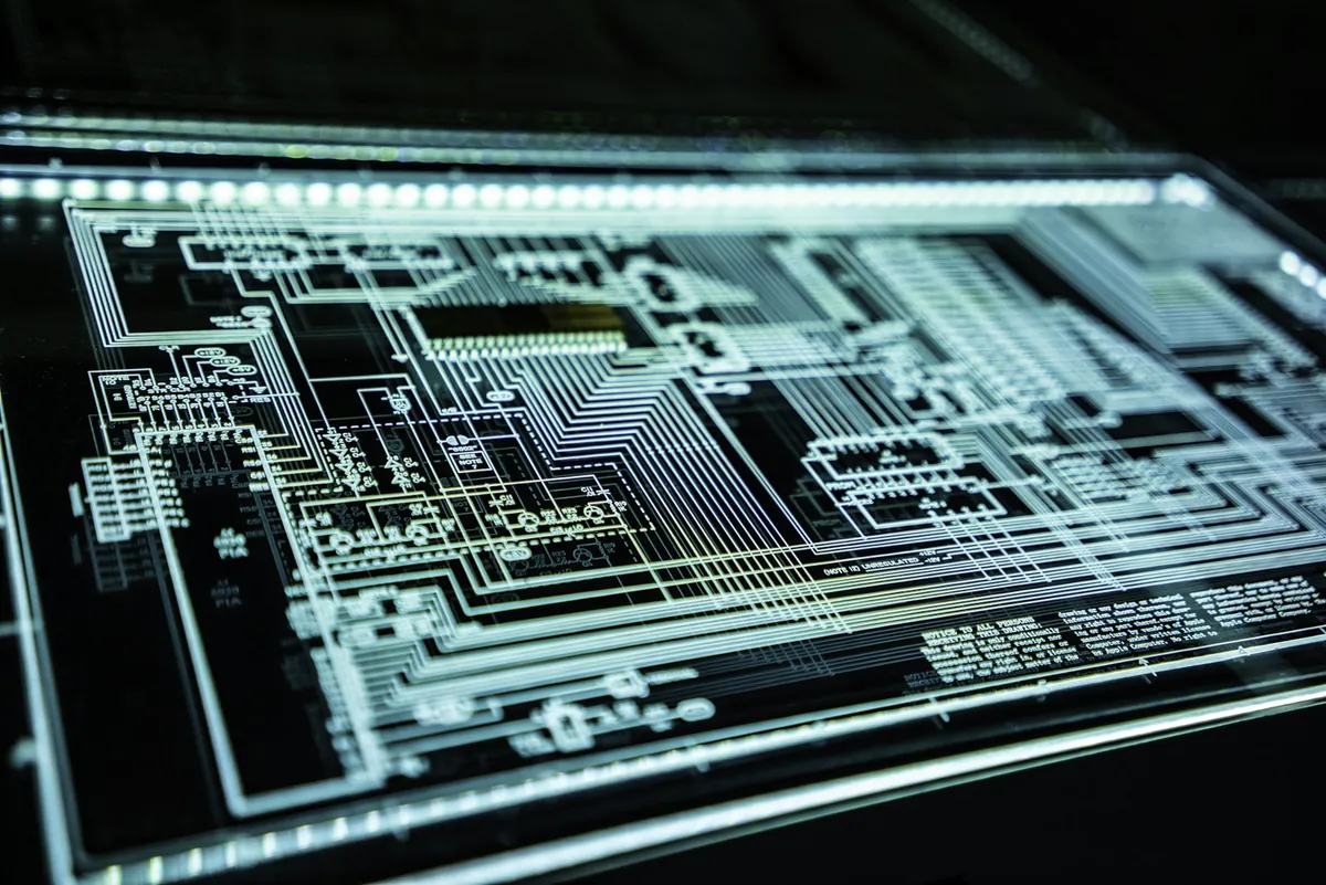 Placa de circuito iluminada con trazos y pistas visibles sobre fondo oscuro